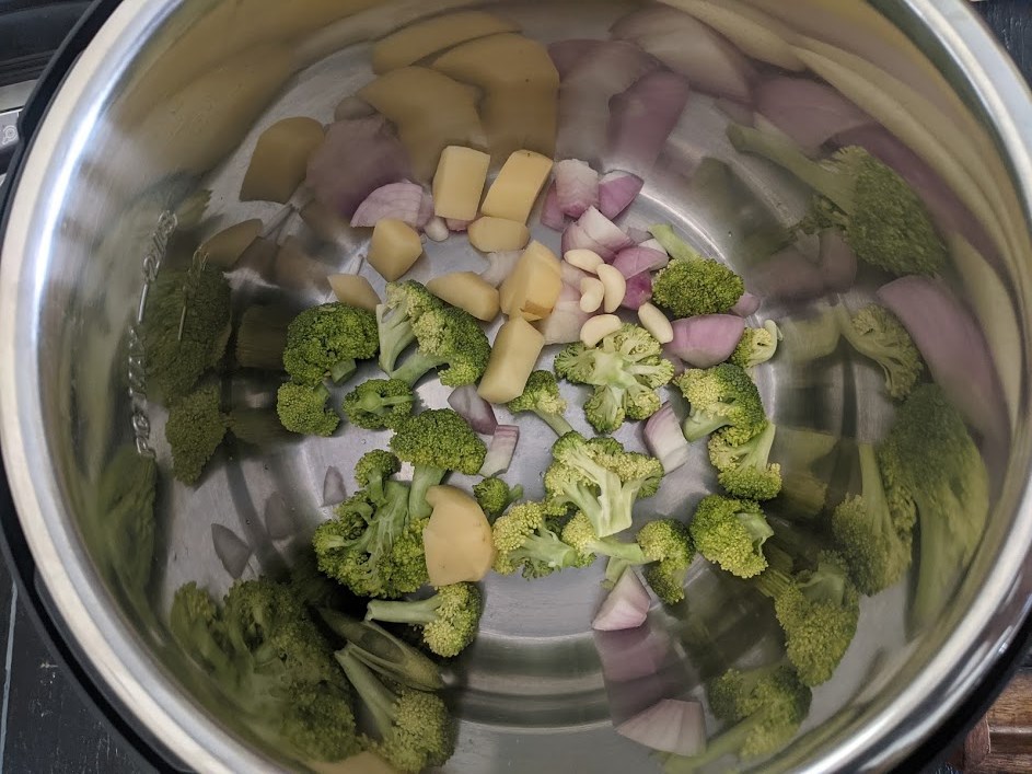 Wash the broccoli florets once and then add them to an Instant Pot, along with this add-in 1 potato cubed and 1 onion cubed and GarlicPods