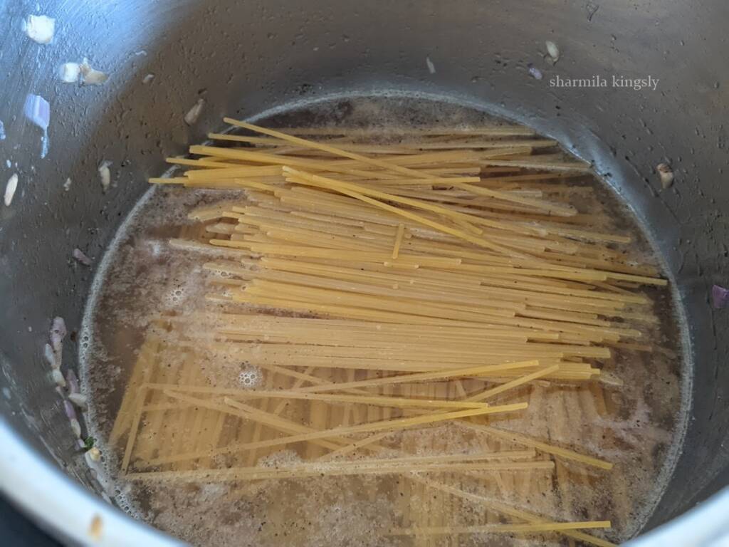 Next, add 1.5 cups of water. Deglaze the pot once. Next, add in 8 oz spaghetti. I am using whole wheat spaghetti. You may break them into half and arrange them in a crisis cross fashion.