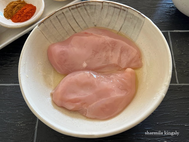 In a mixing bowl add cleaned chicken breasts. Add oil and pat gently on both the sides.